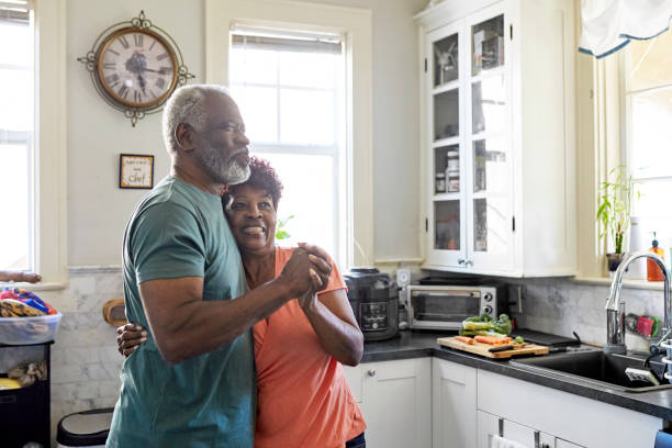 Playful Black seniors embracing and dancing in kitchen