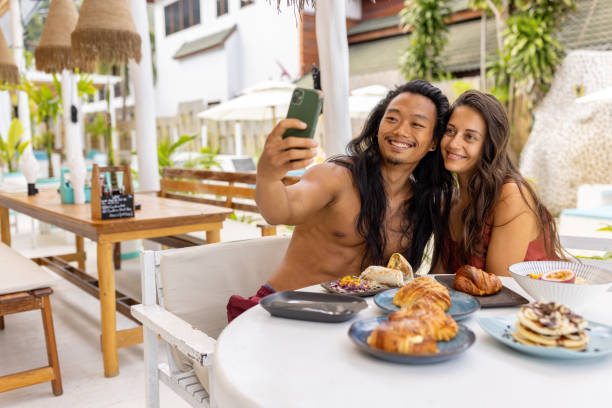 istock Multiracial couple taking selfie, during breakfast at the beach restaurant 1406943945