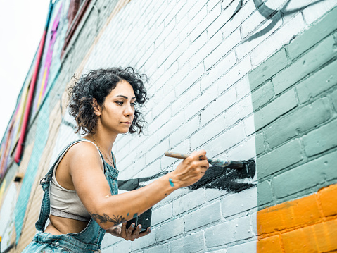 Female artist painting large wall mural