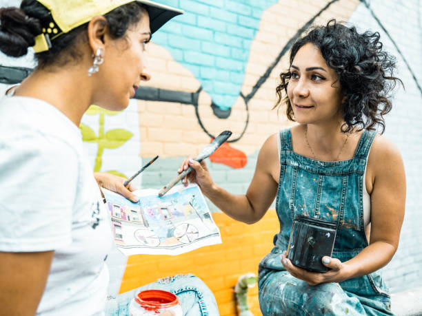 istock Two Female artists taking a break from painting large wall mural 1406946519
