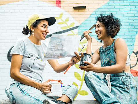 istock Two Female artists taking a break from painting large wall mural 1406946557