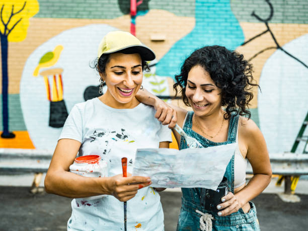 istock Two Female artists taking a break from painting large wall mural 1406946745