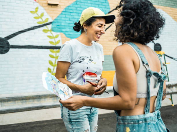 istock Two Female artists taking a break from painting large wall mural 1406946807