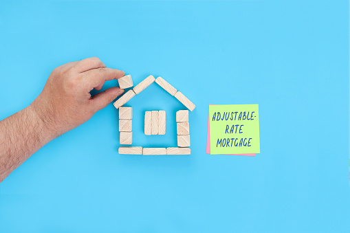 A small house made of wooden blocks and sticky notes with the words Adjustable rate mortgage.