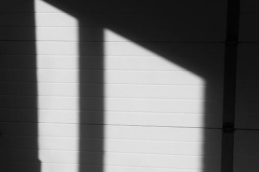 Shadow from the window on the wall with horizontal lines. Black abstract background with reflection of sunlight, view of the building inside