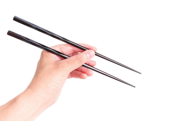 istock Wooden chopsticks in hand against white background 1406953605
