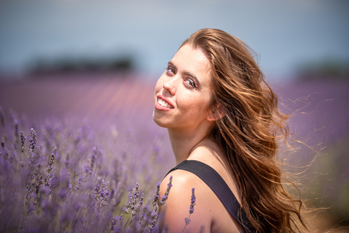 young woman looking at camera crouched in a lavender field in Provence, France