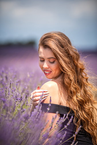 young woman looking his shoulder crouched in a lavender field in Provence, France