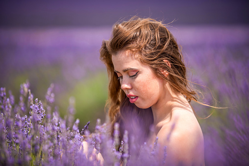 young woman crouched in a lavender field in Provence, France