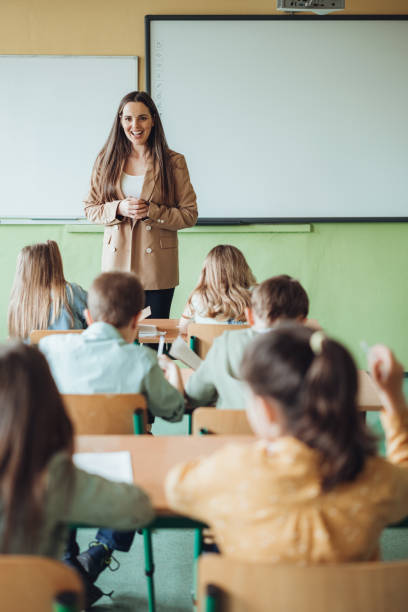 Female teacher teaching students during lecture in classroom stock photo