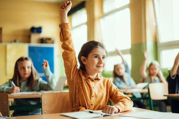 Girls raising hands during lecture in classroom