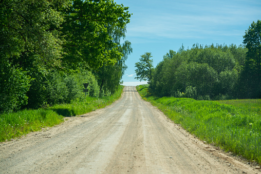 endless beautiful country gravel road in perspective with dust and sun rays above. travel the future