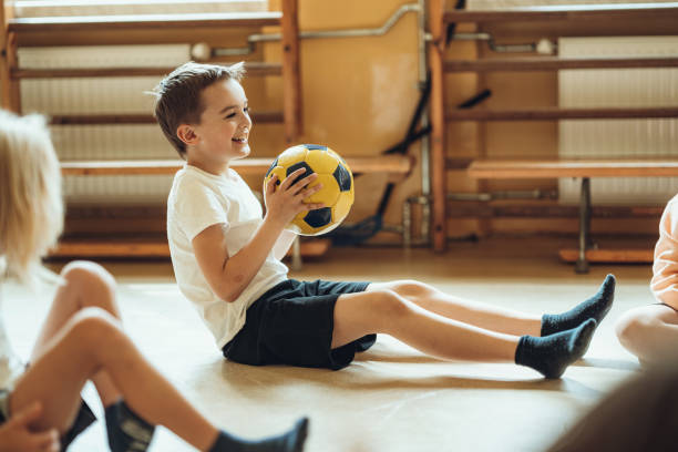 Smiling boy with sports ball during physical education in school stock photo