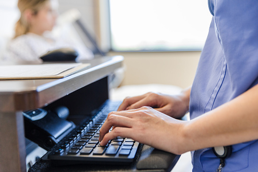 Concéntrese en las manos del trabajador de la salud escribiendo en el teclado de la computadora photo