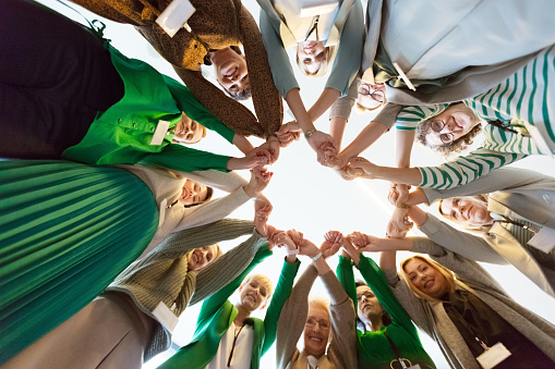 Women’s team. Large group of women holding hands. Low angle view.