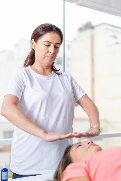 クリニックで患者さんとセラピーをするレイキセラピスト - reiki alternative therapy massaging women ストックフォトと画像