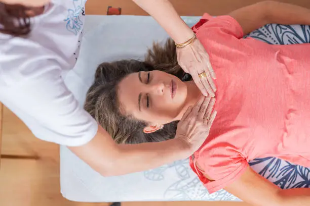 Top view of a professional therapist performing a reiki session to a patient in a clinic