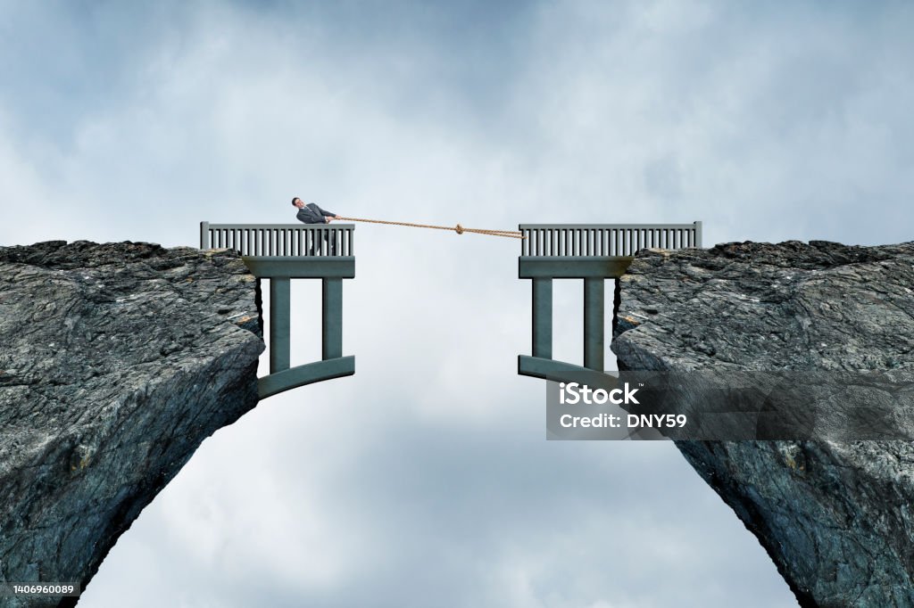 Man Using Rope To Bridge The Gap A man uses a rope in an attempt to bring together a bridge that has a mssing section Separation Stock Photo
