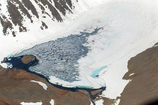 istock Mountain lake covered with ice from a height. Snowfields and glaciers in the mountains 1406960257