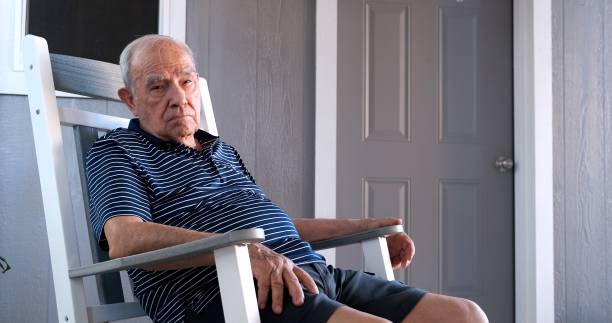 istock Old man sitting in a rocking chair looking at the camera 1406960289
