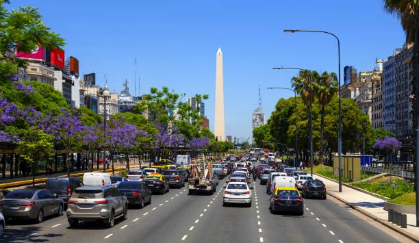 Buenos Aires, Argentina, November 20, 2019: View of the traffic on the main boulevard in Buenos Aires - Avenida 9 de Julio - on a sunny day. In the middle is the Obelisco de Buenos Aires, a national historic monument and icon of the city. It was erected in 1936 to commemorate the quadricentennial of the first foundation of the city.