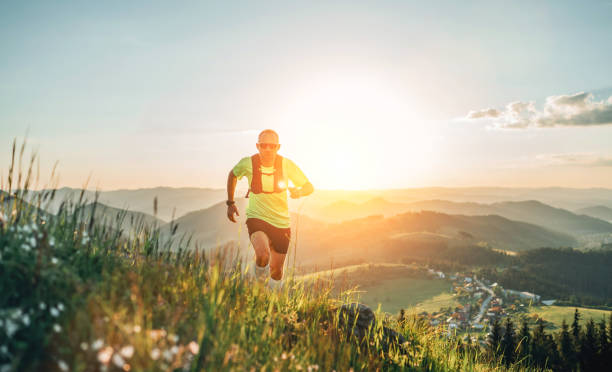 Active mountain trail runner dressed bright t-shirt with backpack in sport sunglasses running endurance marathon race by picturesque hills at sunset time. Sporty active people concept image. corredor de trail de montaña activo vestido de camiseta brillante con mochila en gafas de sol deportivas corriendo carrera maratón de resistencia por pintorescas colinas a la hora del atardecer. imagen de concepto de personas activas deportivas.
