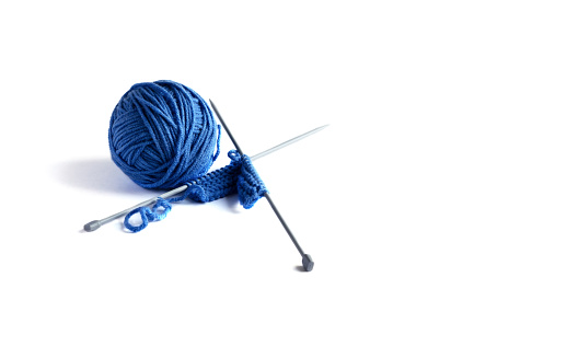 Blue knitted wool on a white background with knitting needles for knitting warm clothes, hobbies