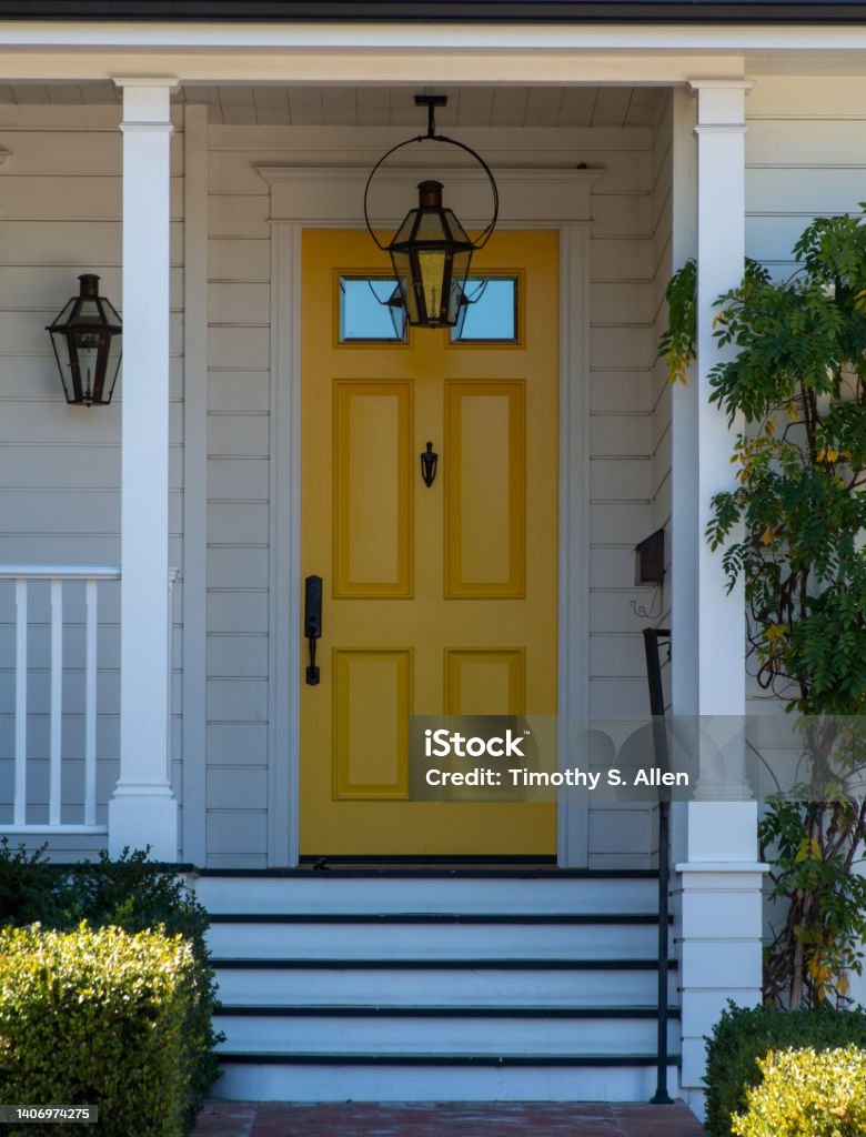 Porch and yellow door Front porch with a narrow stairs leading up to a landing. A yellow door with 2 windows at the top. A door knocker is on the door. A metal mail box is on the right. A hanging porch light is above. Residential Building Stock Photo