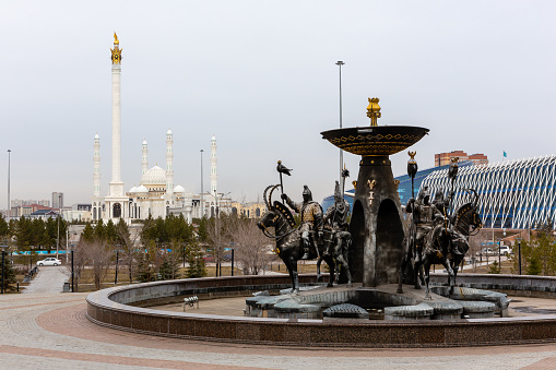Nur Sultan (Astana), Kazakhstan, 11.11.21. Saka Warriors fountain in front of the National Museum of the Republic of Kazakhstan with Kazakh Eli Monument and Hazrat Sultan Mosque in the background.