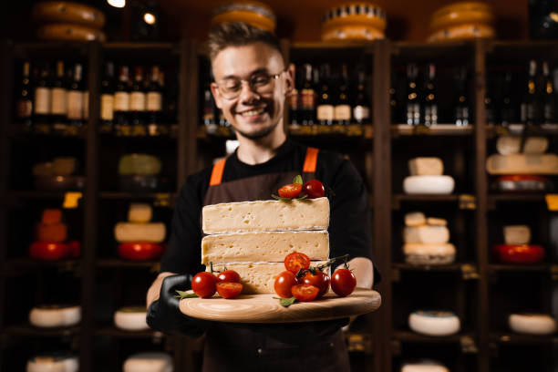 istock Cheese Sommelier holding plate with brie cheese with tomatoes. Creative idea for advertising a cheese shop. 1406979385