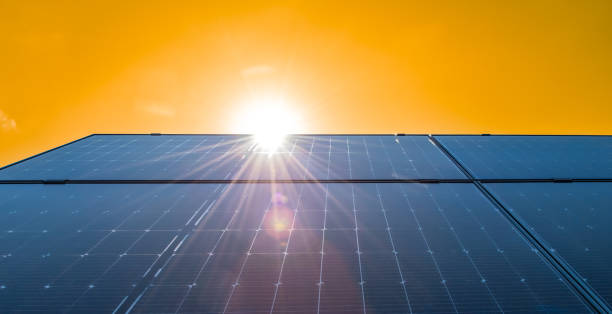 istock Solar panels on roof against bright yellow sky background. 1406981674