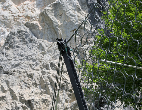 detail of sturdy metal mesh for protection against falling rocks and boulders on the rocky slope in the mountains