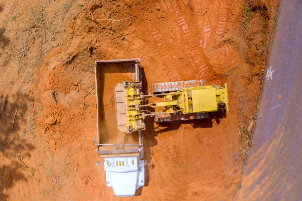 istock Using heavy construction equipment, a excavators loads earth into to dump truck 1406982859