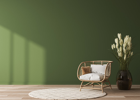 Empty wall mock-up in home interior on green background with rattan chair, wooden table and decor in living room