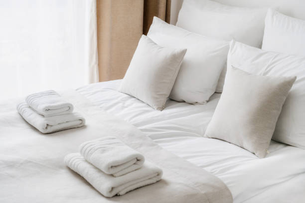 Fresh white bedclothes and towels on bed Cropped view of white bedclothes and towels on bed in comfortable hotel room, hypoallergenic pillows, personal comfort idea, bedding concept, bathroom details airbnb stock pictures, royalty-free photos & images
