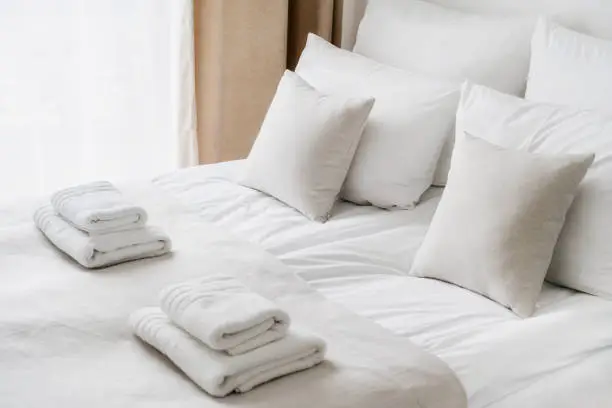 Photo of Fresh white bedclothes and towels on bed