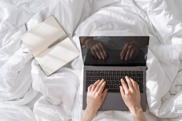 istock Person typing on laptop keybord when staying in bed 1406990634