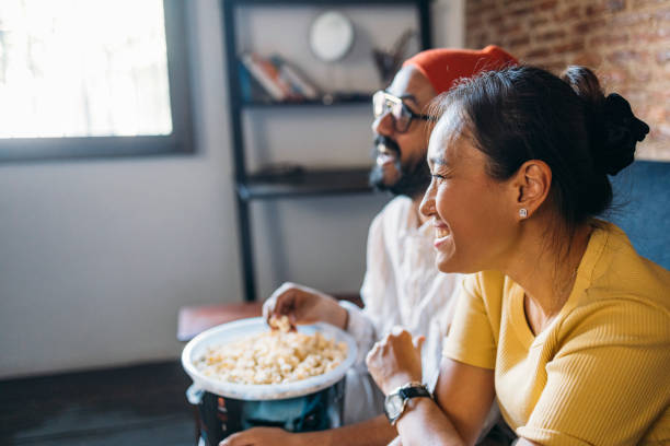 istock A Happy Mixed-race Couple Enjoying Eating Popcorn While Relaxing At Home 1406993028