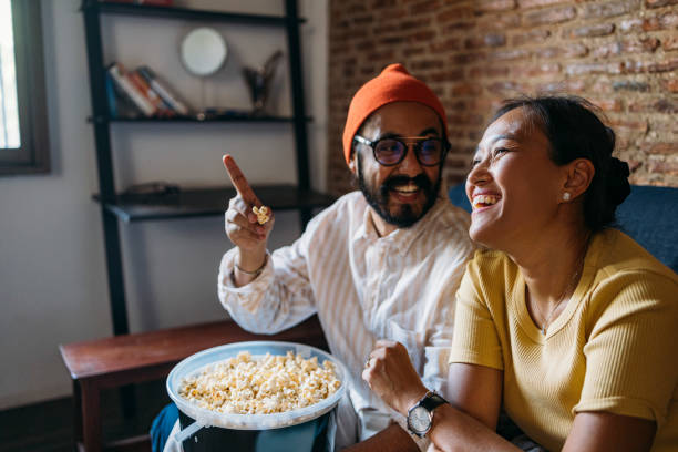 istock A Happy Mixed-race Couple Enjoying Eating Popcorn While Relaxing At Home 1406993034