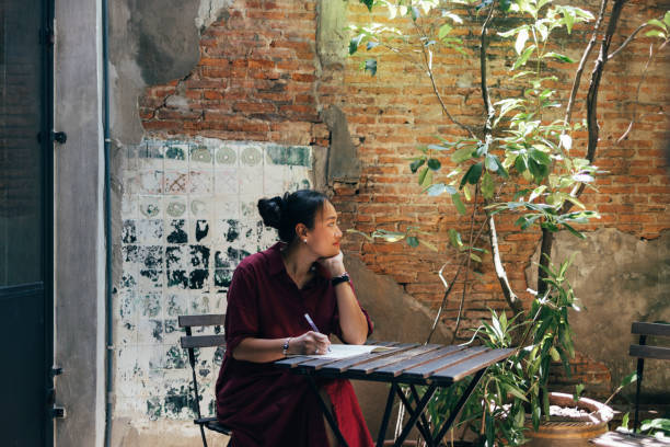 A Smiling Woman Sitting At The Cafe And Studying
