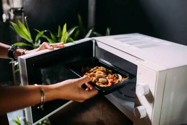 Photo of A Cropped Photo Of An Anonymous Caucasian Female Heating Food In The Oven