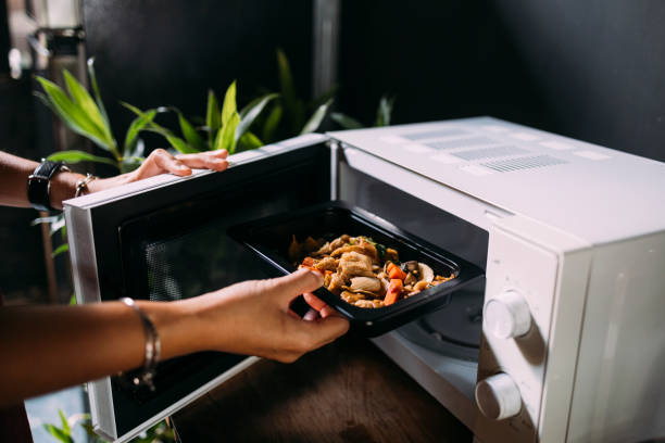a cropped photo of an anonymous caucasian female heating food in the oven - modo de preparação de comida imagens e fotografias de stock