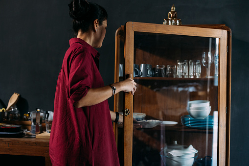 A side view of an anonymous Asian female preparing plates for a meal.