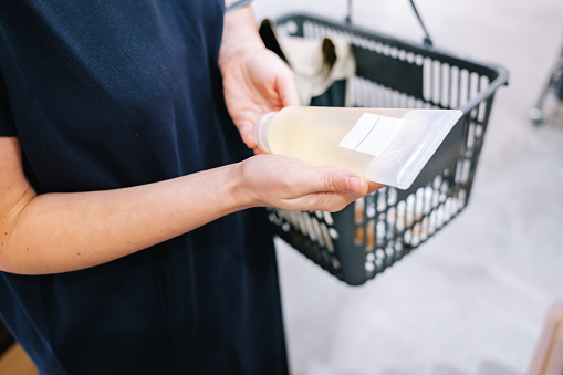 Close up shot of an anonymous woman holding a bottle of some cosmetics.