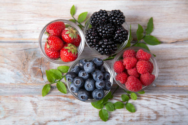istock Assorted berries in glass plates on white rustic wooden table 1406993502