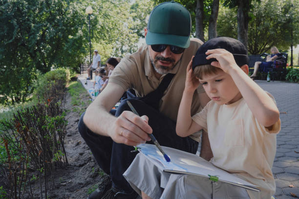 istock Boy painting on easel, father next to him, smiling 1406994555