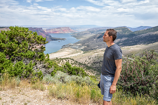 Man standing looking at view over Sheep Creek Overlook in Manila, Utah near Flaming Gorge National Park with cloudy valley and river