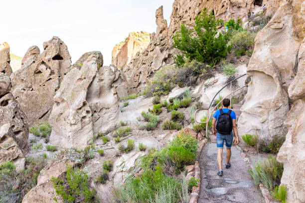 mann wandert im sommer auf dem main loop trail fußweg im bandelier national monument in new mexico, usa mit klippenhöhlenwohnungen, die von ureinwohnern genutzt werden - bandelier national monument anasazi anasazi ruins photography stock-fotos und bilder