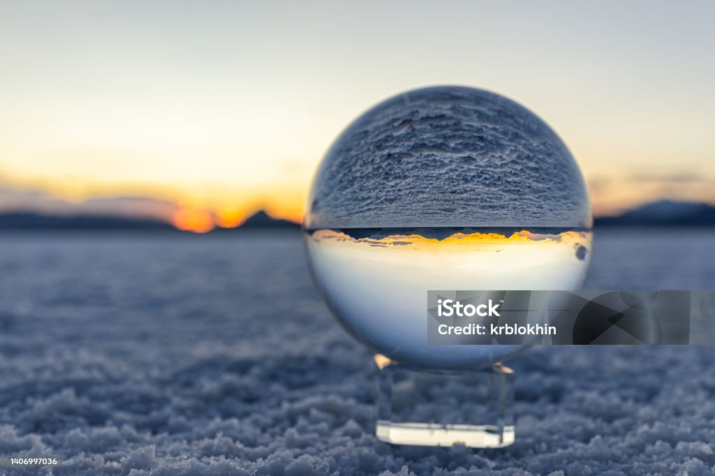Crystal ball macro closeup of view in round glass globe on stand with reflection of Bonneville salt flats and mountains at colorful sunset in Utah desert landscape Circle Stock Photo