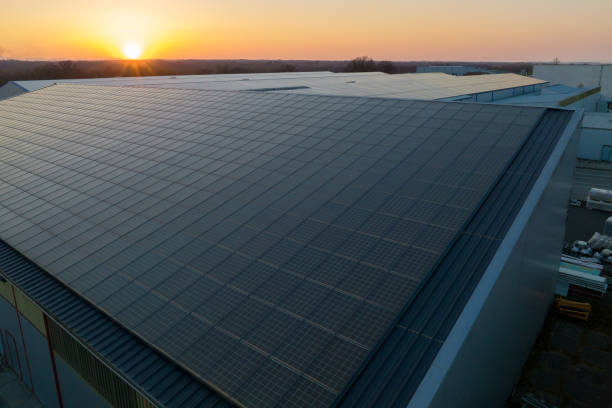 blaue photovoltaik-sonnenkollektoren, die auf dem gebäudedach montiert sind, um bei sonnenuntergang sauberen ökostrom zu erzeugen. konzept zur erzeugung erneuerbarer energien - industry dusk night sustainable resources stock-fotos und bilder